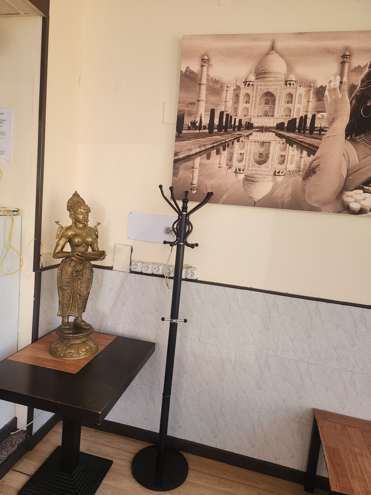 Rincón del restaurante con una figura dorada y un cuadro del Taj Mahal
