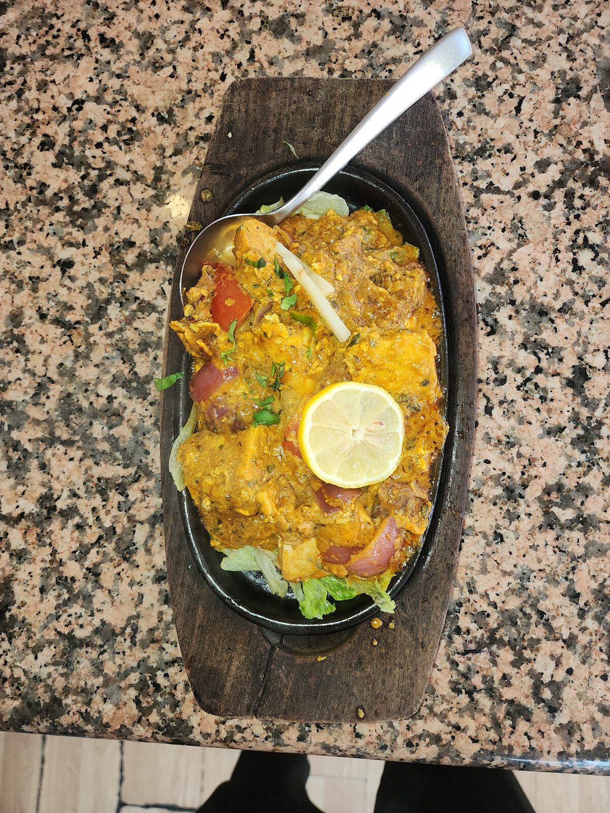 Plato a la plancha servido en sartén de hierro sobre tabla de madera con limón