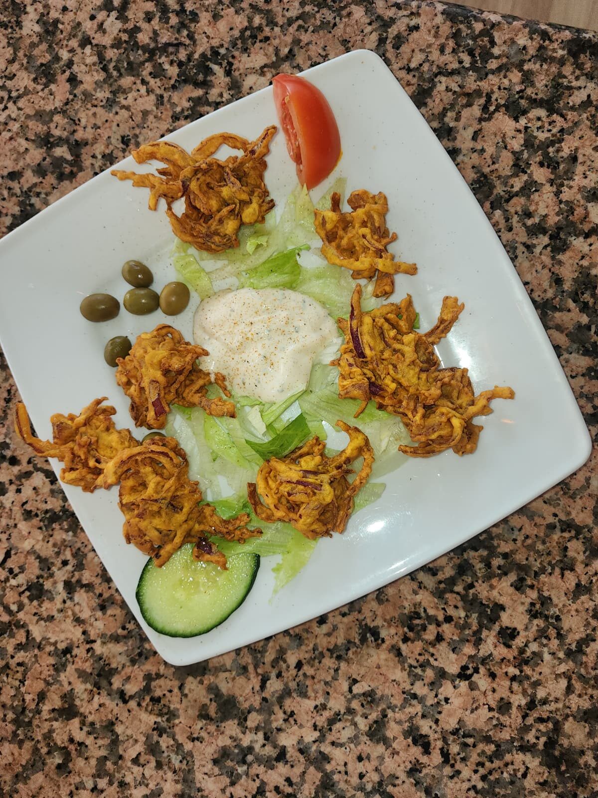 Pakoras de cebolla crujientes con ensalada y salsa de yogur